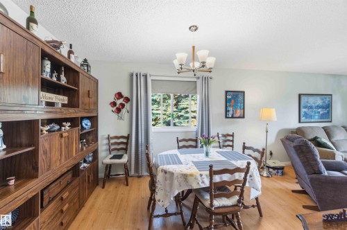 Built-in wood-finish cabinetry, wood-finish flooring, overhead chandelier, and window with exterior view - 30 Cavanagh Crescent, Stony Plain, AB - Indoor Photo Showing Dining Room