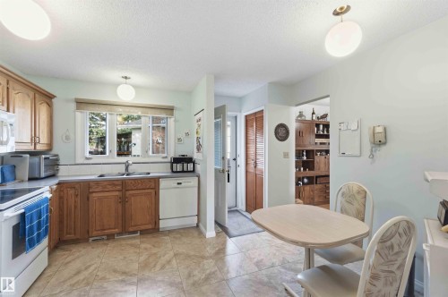 Kitchen featuring ample wood cabinetry, a double basin sink, and tile flooring - 30 Cavanagh Crescent, Stony Plain, AB - Indoor Photo Showing Kitchen With Double Sink