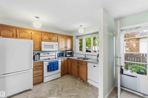 Kitchen featuring wood cabinetry, a double basin sink, and a window above the sink - 30 Cavanagh Crescent, Stony Plain, AB - Indoor Photo Showing Kitchen With Double Sink
