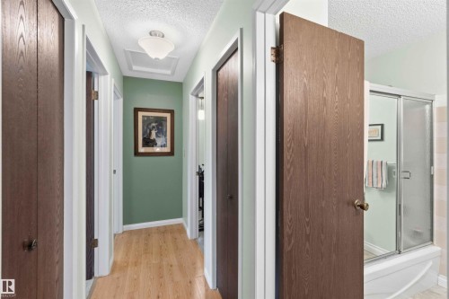 Hallway with wood-finish flooring and multiple doors - 30 Cavanagh Crescent, Stony Plain, AB - Indoor