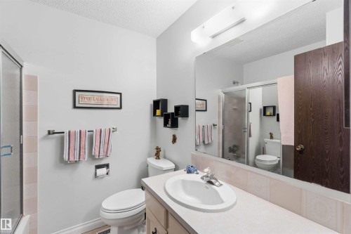 Bathroom featuring a vanity with an integrated sink, a large wall-mounted mirror, a shower enclosure with a sliding glass door, and a toilet - 30 Cavanagh Crescent, Stony Plain, AB - Indoor Photo Showing Bathroom