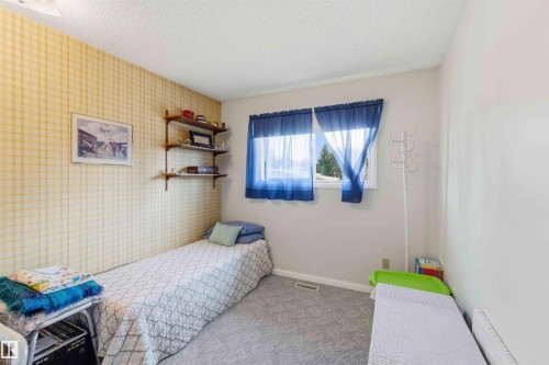Room featuring patterned wallpaper, neutral wall paint, built-in shelving, and carpet flooring - 30 Cavanagh Crescent, Stony Plain, AB - Indoor Photo Showing Bedroom