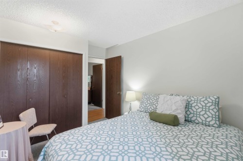 Wood-finish bi-fold closet doors, wall-mounted ceiling light fixture, and light-colored wall paint - 30 Cavanagh Crescent, Stony Plain, AB - Indoor Photo Showing Bedroom
