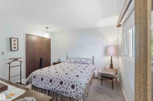 Built-in closet with wood-finish doors, window with roller shade, ceiling-mounted light fixture, and carpeted flooring - 30 Cavanagh Crescent, Stony Plain, AB - Indoor Photo Showing Bedroom