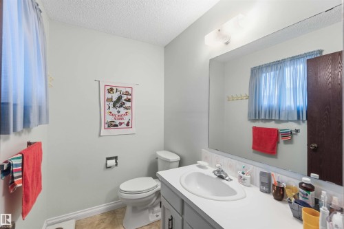 Bathroom featuring a vanity with an integrated sink, a large wall-mounted mirror, and a built-in toilet - 30 Cavanagh Crescent, Stony Plain, AB - Indoor Photo Showing Bathroom