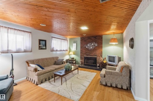 Wood-finish flooring with a wood-paneled ceiling - 30 Cavanagh Crescent, Stony Plain, AB - Indoor Photo Showing Living Room With Fireplace