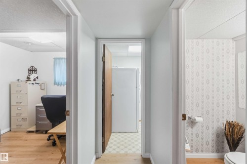 Efficient hallway layout with white painted walls, wood-finish flooring, and multiple doorway entries providing access to adjoining rooms - 30 Cavanagh Crescent, Stony Plain, AB - Indoor
