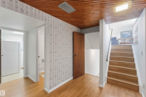 Wood-finish flooring throughout, featuring a wood plank ceiling and a straight staircase with a metal handrail - 30 Cavanagh Crescent, Stony Plain, AB - Indoor Photo Showing Other Room