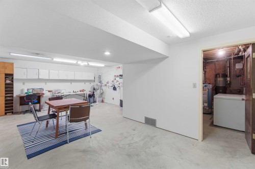 White painted walls, overhead fluorescent lighting, recessed ceiling lighting, and a utility room with a hot water heater - 30 Cavanagh Crescent, Stony Plain, AB - Indoor Photo Showing Laundry Room