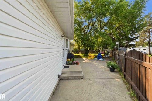 White vinyl siding, concrete walkway, wooden fence, mature trees, and a concrete stoop - 30 Cavanagh Crescent, Stony Plain, AB - Outdoor With Exterior