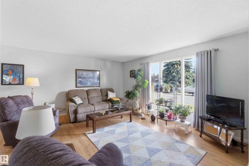 Wood-finish flooring, light-colored walls, large windows, and a textured ceiling - 30 Cavanagh Crescent, Stony Plain, AB - Indoor Photo Showing Living Room