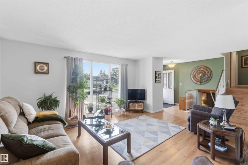 Expansive living area featuring wood-finish flooring, large windows, and a prominent staircase with a wood handrail - 30 Cavanagh Crescent, Stony Plain, AB - Indoor Photo Showing Living Room