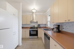 Kitchen featuring light-toned cabinetry, stainless steel appliances, a mosaic tile backsplash, and a double basin sink with a gooseneck faucet - 