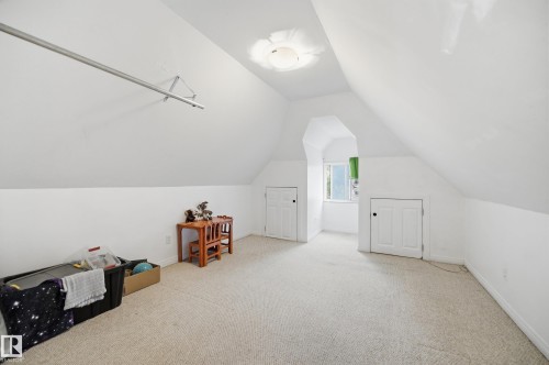 Carpeted room featuring sloped ceilings, a single window, and two built-in storage closets with white panel doors - 10714 103 Street Nw, Edmonton, AB - Indoor Photo Showing Other Room