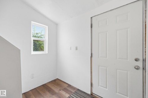 Entryway featuring a white paneled door with silver-tone hardware, wood-finish flooring, and a single-pane window - 10714 103 Street Nw, Edmonton, AB - Indoor Photo Showing Other Room