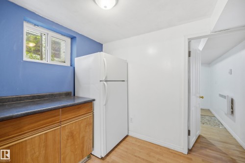 Kitchenette area featuring wood-finish cabinetry, dark countertops, and a white refrigerator - 10714 103 Street Nw, Edmonton, AB - Indoor Photo Showing Other Room