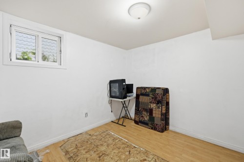 Recessed window with white trim and obscured glass, light wood-finish flooring, white painted walls, and a ceiling-mounted light fixture - 10714 103 Street Nw, Edmonton, AB - Indoor Photo Showing Other Room