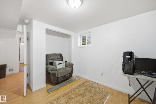 Spacious room with light-toned wood-finish flooring, white walls, and an egress window - 10714 103 Street Nw, Edmonton, AB - Indoor