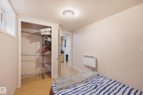 Room featuring light wood-finish flooring, a flush-mount ceiling light fixture, and a built-in wall heater - 10714 103 Street Nw, Edmonton, AB - Indoor Photo Showing Bedroom