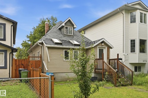 Rear exterior featuring tan siding, an external staircase with wood railings, and a dormer window - 10714 103 Street Nw, Edmonton, AB - Outdoor With Exterior