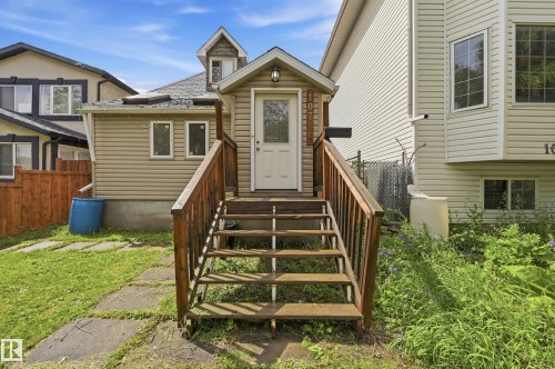 Exterior featuring a front entry with wood steps and railings, beige horizontal siding, a dormer window, and a white entry door - 10714 103 Street Nw, Edmonton, AB - Outdoor