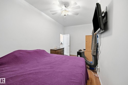 Bright room featuring a vaulted ceiling, wood-finish flooring, a ceiling fan, and a wall-mounted television - 10714 103 Street Nw, Edmonton, AB - Indoor Photo Showing Bedroom