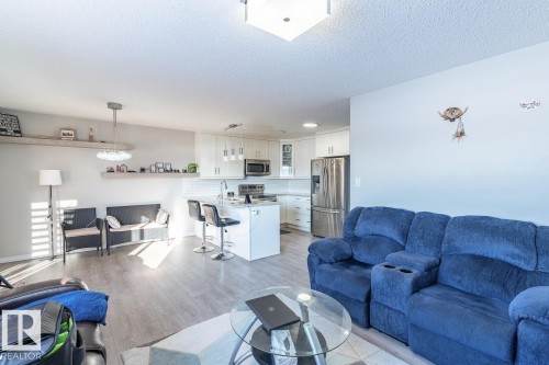 Open-concept living space featuring wood-finish flooring, recessed lighting, and a kitchen island with seating - 1724 27 Street Nw, Edmonton, AB - Indoor