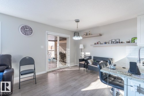 Living area with wood-finish flooring and light gray walls - 1724 27 Street Nw, Edmonton, AB - Indoor Photo Showing Other Room With Fireplace