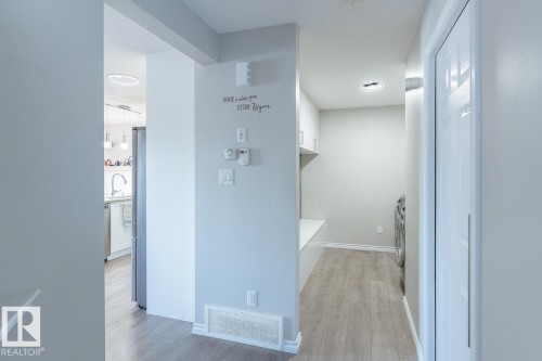 Hallway featuring light wood-finish flooring, a built-in bench, and white cabinetry - 1724 27 Street Nw, Edmonton, AB - Indoor Photo Showing Other Room