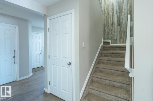 Carpeted staircase with white handrail and wood-finish accent wall - 1724 27 Street Nw, Edmonton, AB - Indoor Photo Showing Other Room