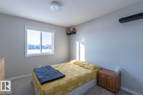 Room featuring a large window, neutral wall paint, ceiling-mounted light fixture, and light-colored carpeting - 1724 27 Street Nw, Edmonton, AB - Indoor Photo Showing Bedroom