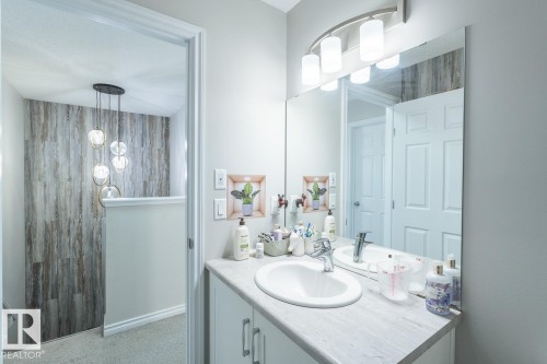 Bathroom vanity featuring a single basin sink, chrome faucet, and expansive wall-mounted mirror - 1724 27 Street Nw, Edmonton, AB - Indoor Photo Showing Bathroom