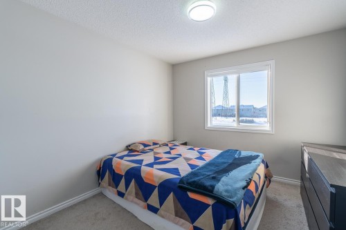 Bedroom featuring light gray walls, plush gray carpeting, white baseboards, a white-framed window, and a flush-mount ceiling light - 1724 27 Street Nw, Edmonton, AB - Indoor Photo Showing Bedroom