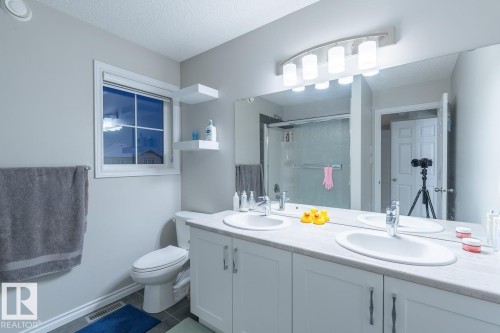 Bathroom featuring a double vanity with integrated sinks, white cabinetry, and a full-width mirror - 1724 27 Street Nw, Edmonton, AB - Indoor Photo Showing Bathroom