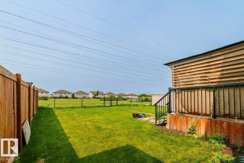 Expansive rear yard featuring green lawn, wood privacy fence, and a multi-level deck with black railings - 1724 27 Street Nw, Edmonton, AB - Outdoor