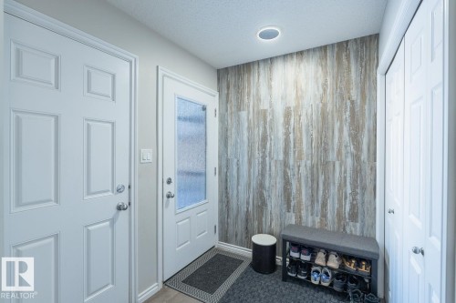 Entryway featuring a wood-finish accent wall, white paneled doors, frosted glass door insert, recessed lighting, and light wood-finish flooring - 1724 27 Street Nw, Edmonton, AB - Indoor Photo Showing Other Room