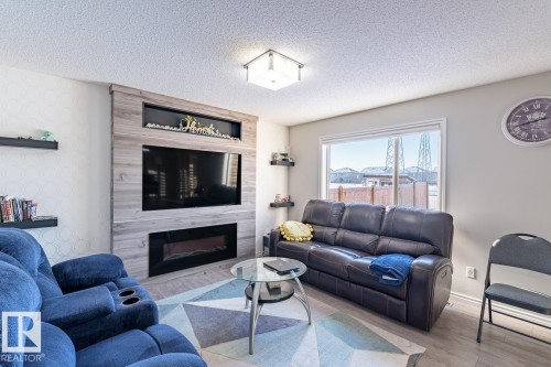 Living area featuring a custom entertainment wall with wood-finish paneling, an integrated electric fireplace, and a television recess - 1724 27 Street Nw, Edmonton, AB - Indoor Photo Showing Living Room With Fireplace