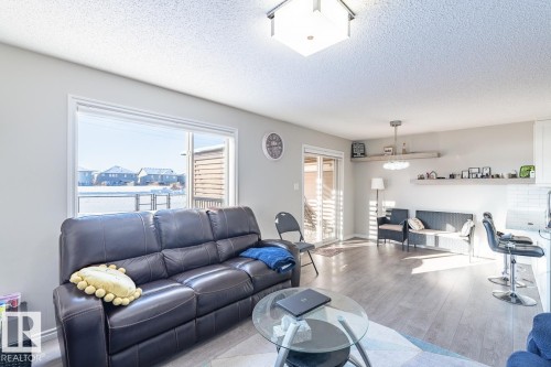 Spacious living area featuring light gray walls, wood-finish flooring, and a large picture window - 1724 27 Street Nw, Edmonton, AB - Indoor Photo Showing Living Room