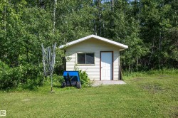 Exterior storage shed with white vinyl siding, white trim, and a white entry door, set on a concrete pad - 