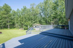 Expansive wood-finish deck with integrated steps, railing, and exterior wall sconces - 