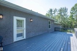 Exterior deck featuring a screened door entry, dark gray wood flooring, and perimeter railing - 