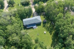 Aerial perspective highlighting a residential structure with a shingled roof, surrounded by mature trees - 