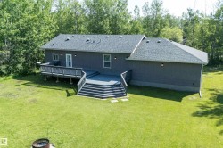 Multi-level deck with steps leading to a manicured lawn, framed by a house with dark gray siding and a gray shingle roof - 