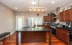 Kitchen featuring wood-finish flooring, dark cabinetry, and black countertops - 