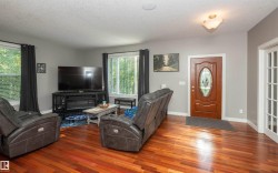 Spacious interior featuring wood-finish flooring, a built-in electric fireplace, recessed ceiling lighting, a decorative front entry door with an oval glass insert, and a white French door - 