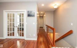 Hardwood flooring throughout a spacious hallway featuring contemporary recessed lighting - 