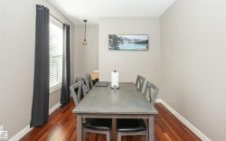 Dining area featuring wood-finish flooring, a pendant light fixture, and a window with blinds - 
