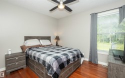 Spacious room featuring wood-finish flooring, a contemporary ceiling fan, and a large window with horizontal blinds - 