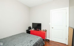 Room featuring light gray walls, wood-finish flooring, and a white panel door with a curved top detail - 