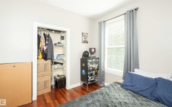 Bedroom featuring wood-finish flooring, a window with blinds, and a built-in closet with wire shelving and a hanging rod - 